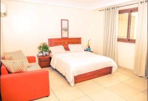 a bedroom with a bed and a red couch at Hannatel Rooms Liberté in Douala