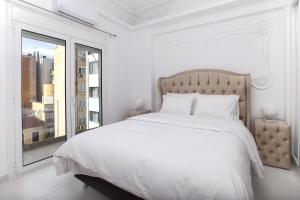 a white bedroom with a large bed and a window at Elysian Haven in Athens