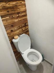 a white toilet in a bathroom with a wooden wall at Perle marine Diamant in Le Diamant