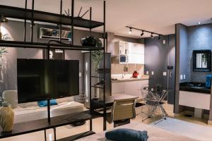 a living room with a large television and a kitchen at Flat Studio DNA Smart style in Goiânia
