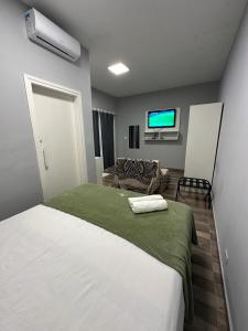 a bedroom with a large white bed and a couch at Pousada José Marineli in São Francisco do Sul