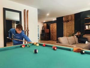 a man playing pool in a living room at La Belle Excuse in Saint-Joachim
