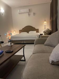 a bedroom with a bed and a couch and a table at Al Jadeed Istudio In Al Jubaylah in Al ‘Uyaynah