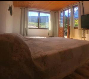 1 dormitorio con 1 cama grande, ventanas y TV en Pouso Casazul en Tiradentes