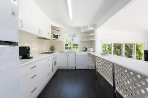 una cocina blanca con armarios blancos y una escalera en Coastal Chill, en Port Douglas