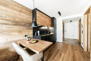 cocina con pared de madera y mesa de madera en Allgäu Luxury Apartment Berglöwe mit Sauna, en Oberstaufen