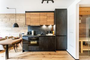 a kitchen with black cabinets and a wooden table at Allgäu Luxury Apartment Berglöwe mit Sauna in Oberstaufen