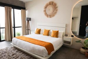 a bedroom with a large bed with orange pillows at Aura Hotel boutique in Guadalajara