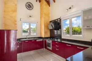 a kitchen with red cabinets and a clock on the wall at Villa Lynko - 3 Chambres Climatisées - Jardin Tropical - Plages du Moule à 10 minutes in Le Moule
