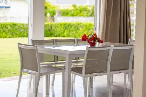 a white table and chairs with a vase of flowers on it at Villa Lynko - 3 Chambres Climatisées - Jardin Tropical - Plages du Moule à 10 minutes in Le Moule