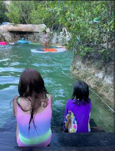 two girls sitting on the bank of a river at El Cenote 11:11 in Tulum