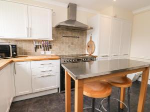 a kitchen with white cabinets and a stove top oven at Oak Cottage in Torcastle