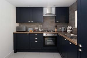 eine Küche mit dunkelblauen Schränken und einem Waschbecken in der Unterkunft Ascot Cottage in Cirencester