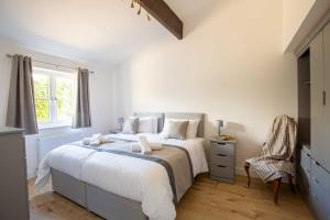 ein Schlafzimmer mit einem großen Bett und einem Stuhl in der Unterkunft Ascot Cottage in Cirencester