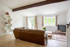 ein Wohnzimmer mit einem braunen Sofa und einem TV in der Unterkunft Ascot Cottage in Cirencester
