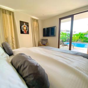a bedroom with a large bed with a view of a pool at Jan Sofat LUX A5 in Willemstad