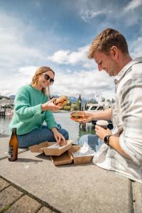 a man and a woman sitting on the ground eating pizza at LyLo Queenstown in Queenstown