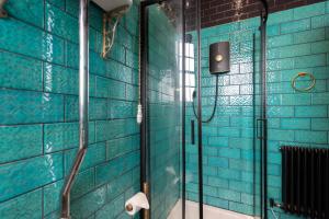 a bathroom with a shower with blue tiled walls at Dickens Nook in Hartlepool