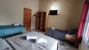 Habitación pequeña con 2 camas y TV. en Apart clemencia, en Puerto Iguazú