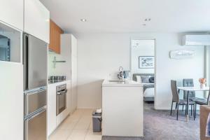 eine Küche mit weißen Geräten und ein Esszimmer in der Unterkunft Serene 2Bed Gem with Free Parking in Auckland