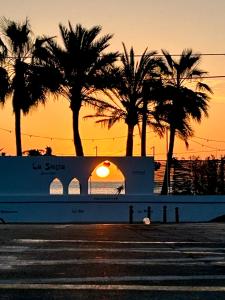 a boat with palm trees in front of a sunset at Casita Bonita - with private garden near beach in Jávea in Jávea