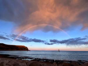 a rainbow in the sky over the ocean with a sailboat at Casita Bonita - with private garden near beach in Jávea in Jávea