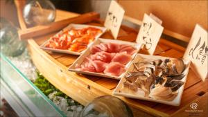 a table with three trays of different types of seafood at Daiwa Roynet Hotel Hachinohe in Hachinohe