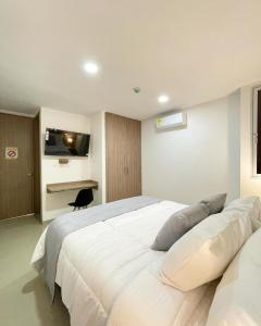 - une chambre avec un grand lit blanc et un bureau dans l'établissement Hotel Olam Deluxe Valledupar, à Valledupar