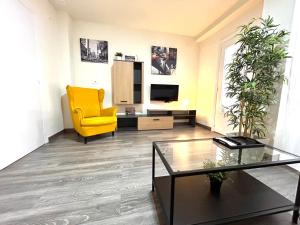 sala de estar con silla amarilla y TV en Plaza Circular Más que apartamentos en Murcia