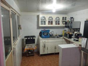 cocina con armarios blancos, fregadero y fogones en Habitación privada en Casa compartida, 4 adultos, en Ciudad de México