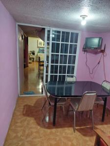 uma mesa de jantar com cadeiras e uma televisão na parede em Habitación privada en Casa compartida, 4 adultos em Cidade do México