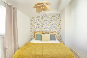 1 cama con manta amarilla y ventilador de techo en Petit aixois centre historique avec clim, en Aix-en-Provence