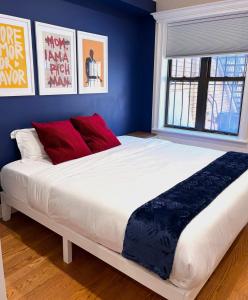 Una cama grande con almohadas rojas en un dormitorio azul. en SWJ544 - Chic 1BR in the Heart of NYC, en Nueva York