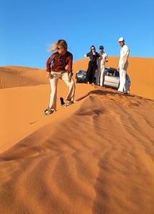 un gruppo di persone che si trovano sulla cima di una duna di sabbia di Horaz Merzouga Camp a Merzouga Altre 120 foto