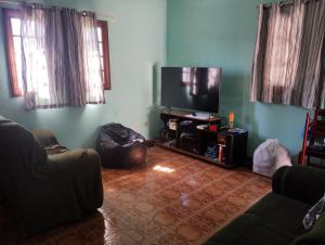 een woonkamer met een bank en een flatscreen-tv bij Perequê Mirim, Caraguatatuba in Caraguatatuba