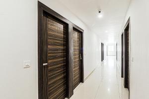 un pasillo con puertas de madera en un pasillo blanco en Oak Wood Inn, en Rājpur