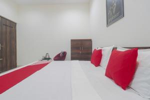 een groot wit bed met rode kussens erop bij OYO Hotel Bella Ciao in Ludhiana