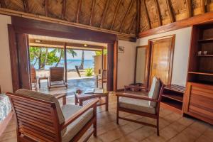 una sala de estar con sillas y mesas y vistas al océano. en Toberua Island Resort, en Toberua