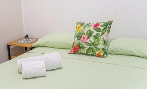 a green bed with a pillow and a wooden table at Hostel Gato Colonial in Santo Domingo