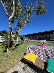 a bed with a yellow pillow sitting on a bench at Beach holiday - private setting. in Whiritoa