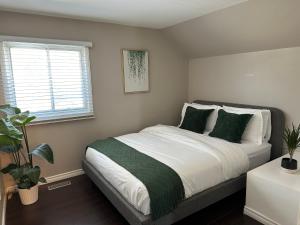 1 dormitorio con 1 cama grande con almohadas verdes en Entire house with Park parking in large backyard, en Richmond Hill