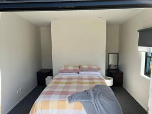 a bedroom with a bed with a plaid blanket at Beach holiday - private setting. in Whiritoa