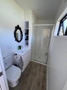 a white bathroom with a toilet and a shower at Beach holiday - private setting. in Whiritoa