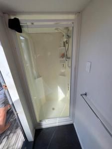 a bathroom with a shower with a glass door at Beach holiday - private setting. in Whiritoa
