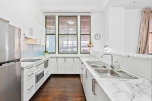 La cuisine blanche est équipée d'un évier et d'un réfrigérateur. dans l'établissement Inner City Retreat 1BD Pyrmont - 302, à Sydney