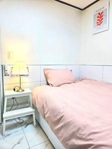 - une chambre blanche avec un lit rose et une table de nuit dans l'établissement [New]Seongsu/Konkuk U/PoguniStay, à Séoul