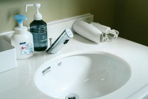 a bathroom sink with a bottle of cleaner and a phone at TESHIKAGA HOSTEL MISATO in Teshikaga