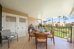 a dining room with a table and chairs and a balcony at Kamaole Sands 7307 in Wailea