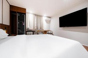 a bedroom with a large bed and a flat screen tv at H Avenue Hotel Chungjangro in Gwangju