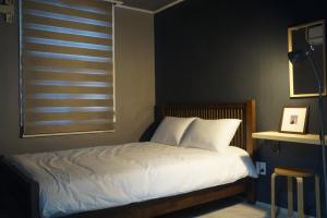 a bedroom with a bed with white sheets and a window at Art and Stay in Suncheon